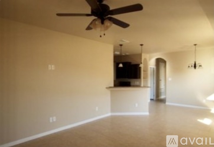 A spacious room with a ceiling fan and a light on.