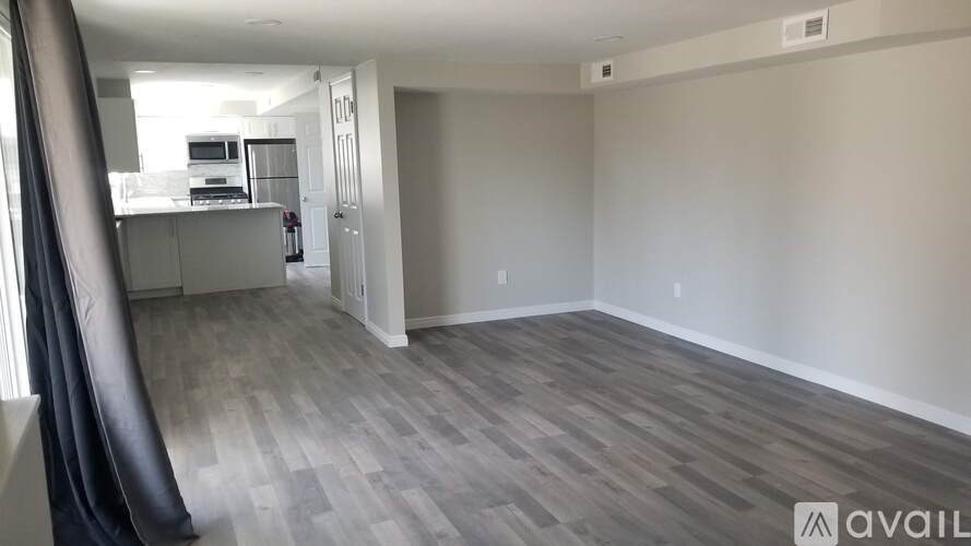 A spacious living room with a kitchen in the background and a grey floor.