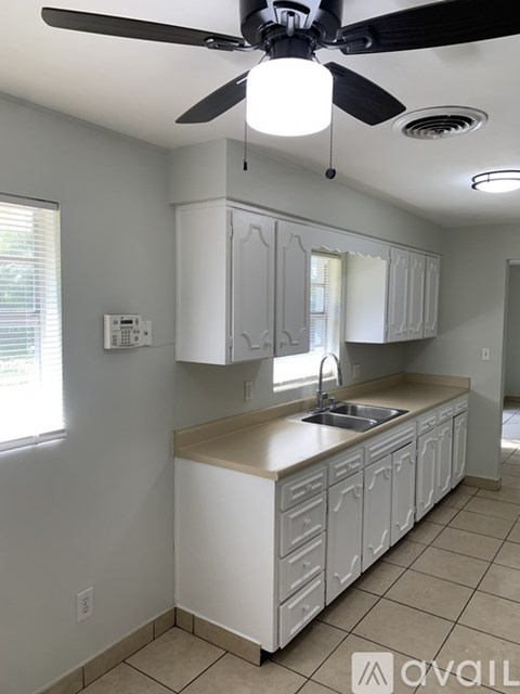 A kitchen with white cabinets and a ceiling fan.