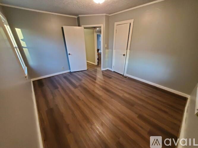 A room with wooden flooring and two doors.