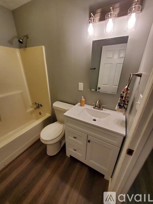 A bathroom with a toilet, sink, and mirror.