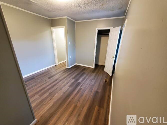 A room with wooden flooring and a door on the right side.