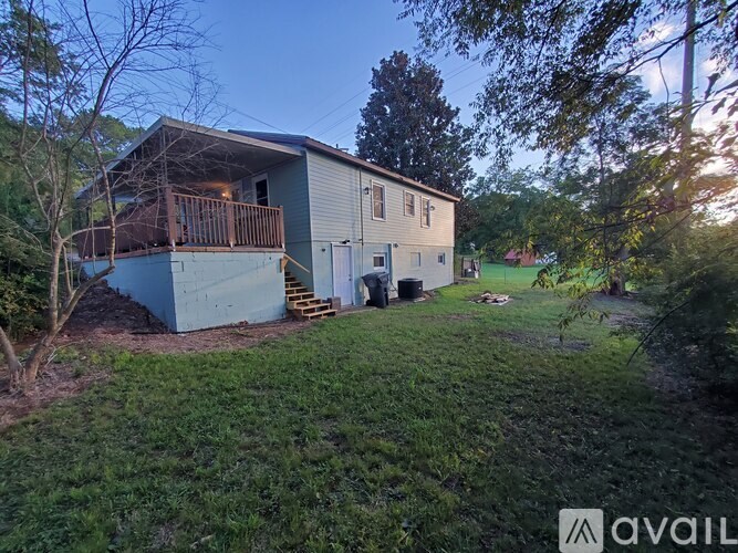 A house with a deck and a garage is surrounded by trees.