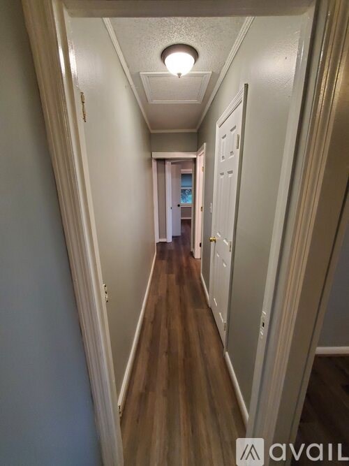 A long hallway with white walls and wood floors.