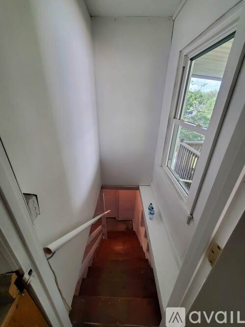 A stairway with a railing and a window overlooking a deck.