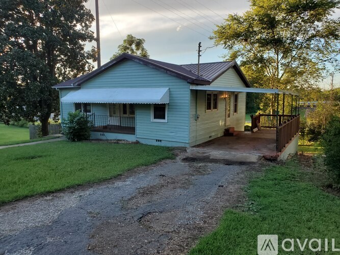 A blue house with a porch and a gravel driveway.