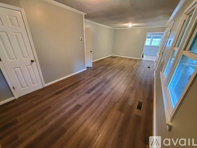 A room with wooden flooring and a door on the left side.