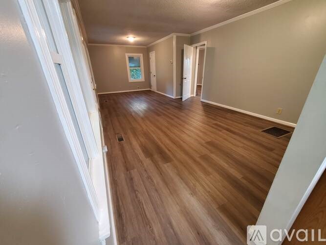 A room with wooden flooring and white walls.