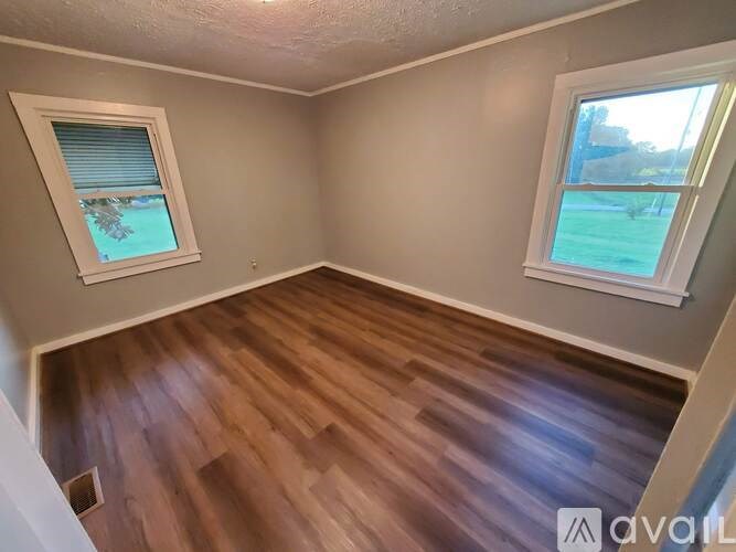 A room with wooden flooring and a window with blinds.