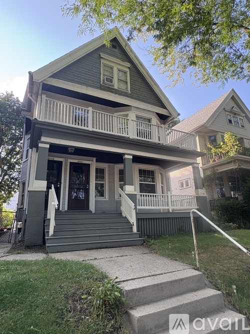 A two-story house with a front porch and stairs leading up to the entrance.