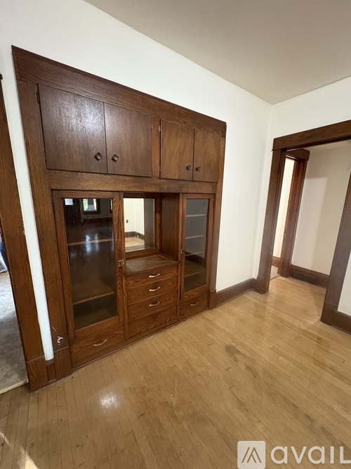 A room with wooden floors and a large wooden cabinet with glass doors.