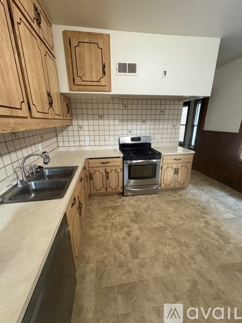 A kitchen with wooden cabinets and a tiled backsplash.