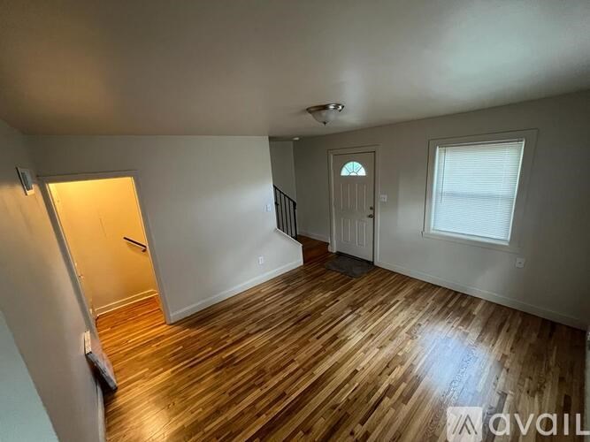 A room with wooden flooring and a door leading to another room.