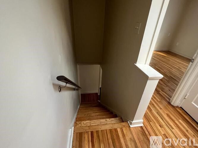 A hallway with wooden floors and white walls.