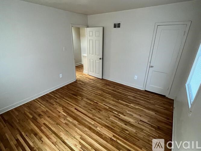 A room with wooden flooring and two white doors.