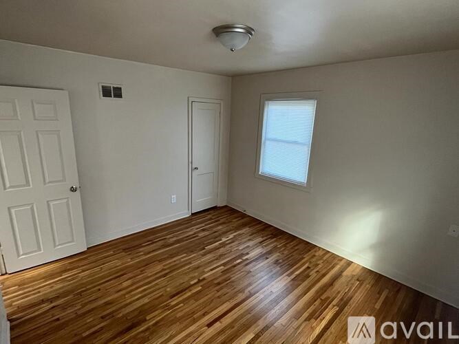 A room with wooden flooring and a window with blinds.