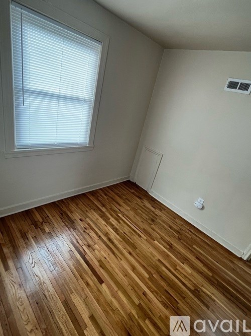 A room with wooden flooring and a window with blinds.