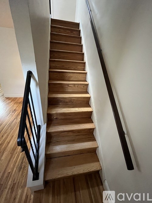 A wooden staircase with a black handrail.