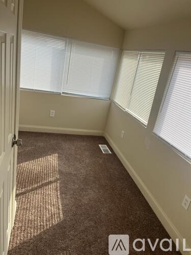 A room with a carpeted floor and a door on the left.