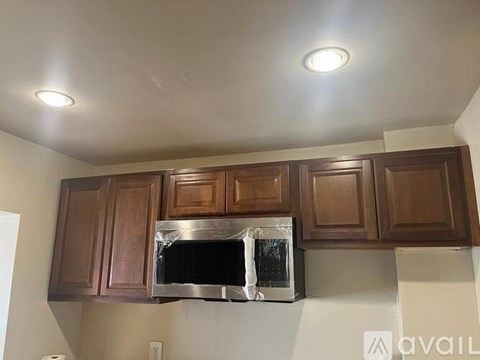 A kitchen with brown cabinets and a stainless steel microwave.