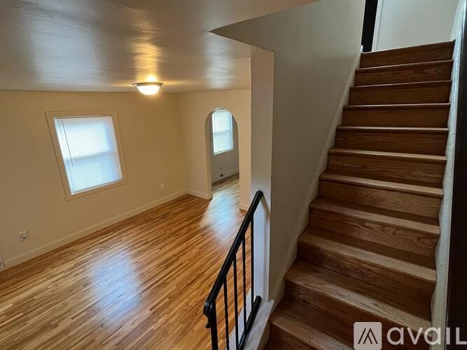 A wooden staircase with a black railing leads up to a doorway.