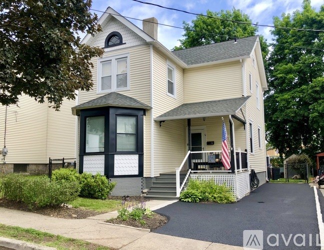A house with a flag on the porch and a driveway in front.