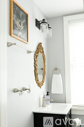 A bathroom with a white sink and a mirror with a gold frame.