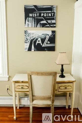 A chair and a table with a lamp on it in front of a wall with posters.
