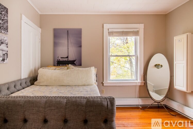 A bedroom with a bed, a window, and a picture on the wall.