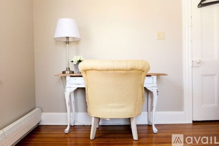 A white desk with a yellow chair and a white lamp.