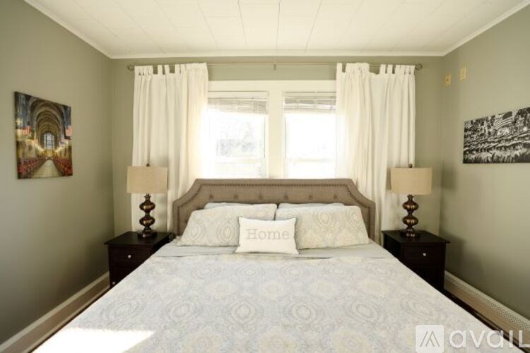 A bedroom with a large bed, two lamps, and a painting on the wall.