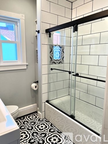 A bathroom with a black and white floor and a glass shower door.