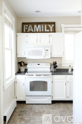 A white kitchen with a sign that says "FAMILY" on the wall.