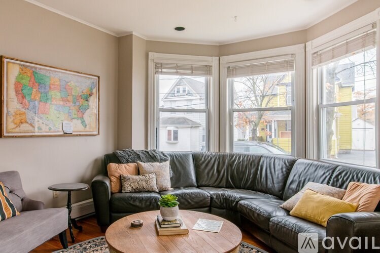 A living room with a grey couch and a map of the United States on the wall.