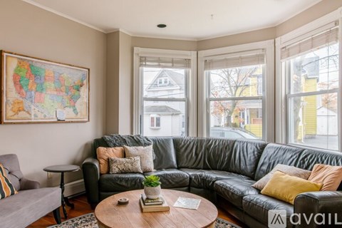 A living room with a grey couch and a map of the United States on the wall.