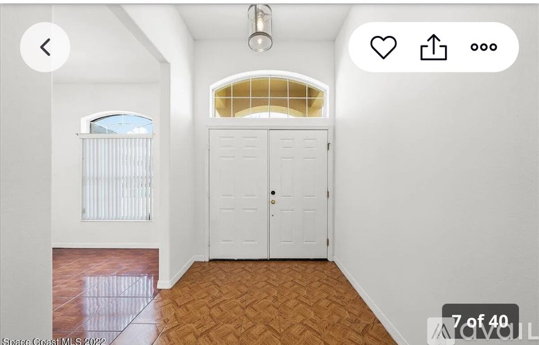 A room with a white door and a window with a view of the sky.