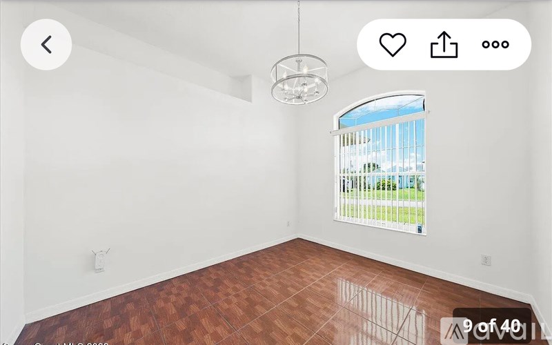 A room with a wooden floor and a window with blinds.