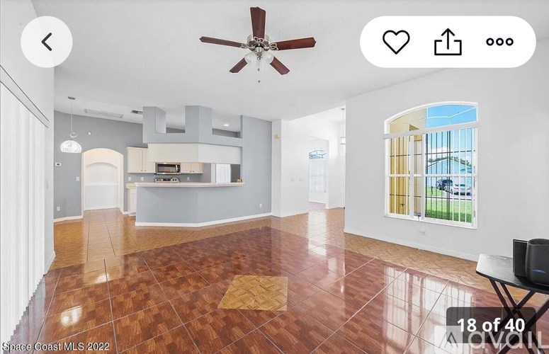 A spacious room with a ceiling fan and a large window.