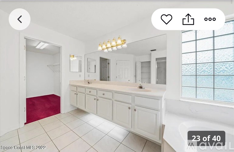 A white bathroom with a red rug and a window overlooking the ocean.