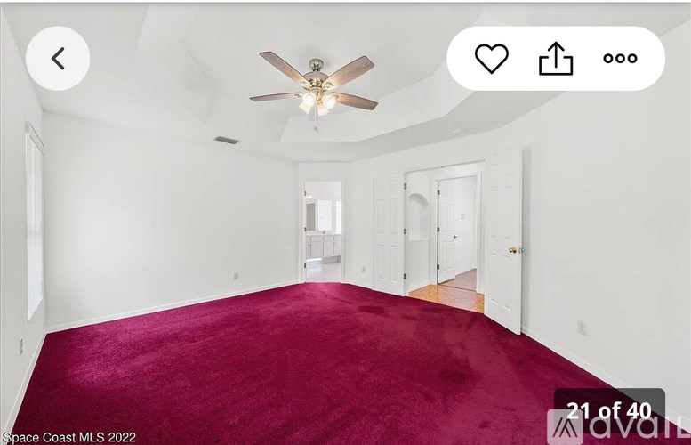 A room with a red carpet and a ceiling fan.