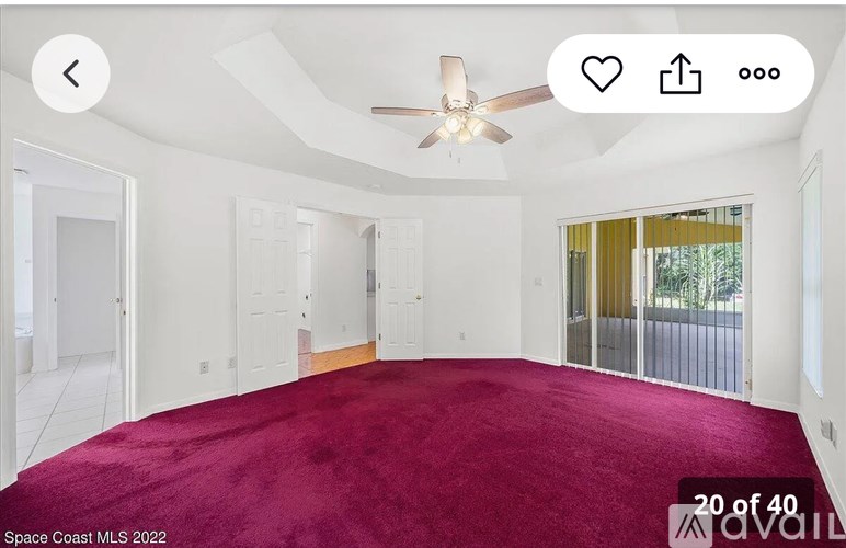 A room with a red carpet and a ceiling fan.