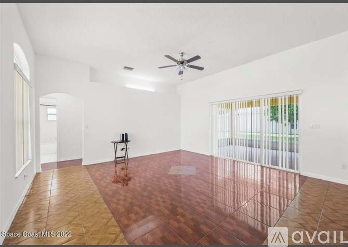 A room with a ceiling fan and a wooden floor.