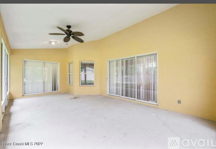 A spacious room with a ceiling fan and sliding glass doors.