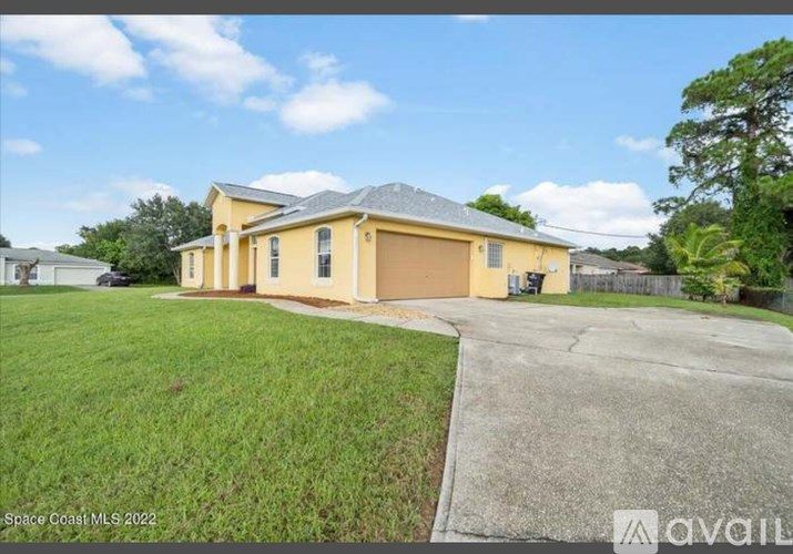 A yellow house with a grey roof is for sale in Space Coast MLS 2022.