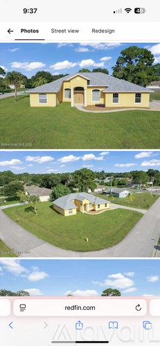 A yellow house with a grey roof and a green lawn.
