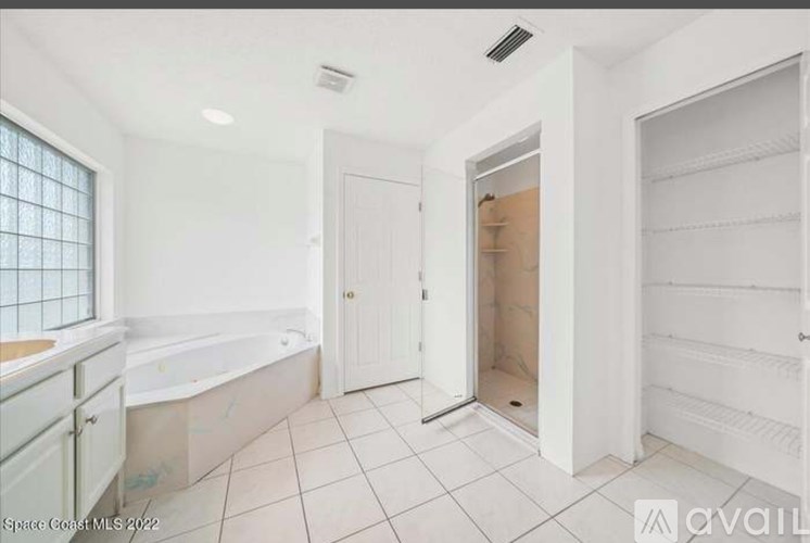 A bathroom with a tub, sink, and a door open to another room.