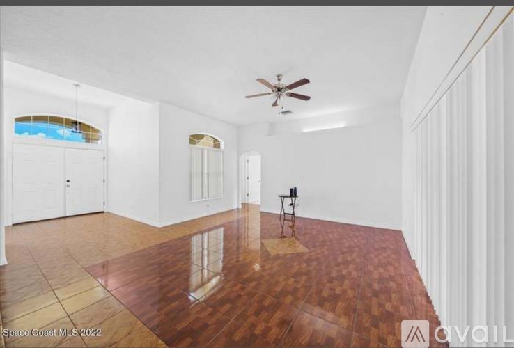 A spacious room with wooden flooring and a ceiling fan.