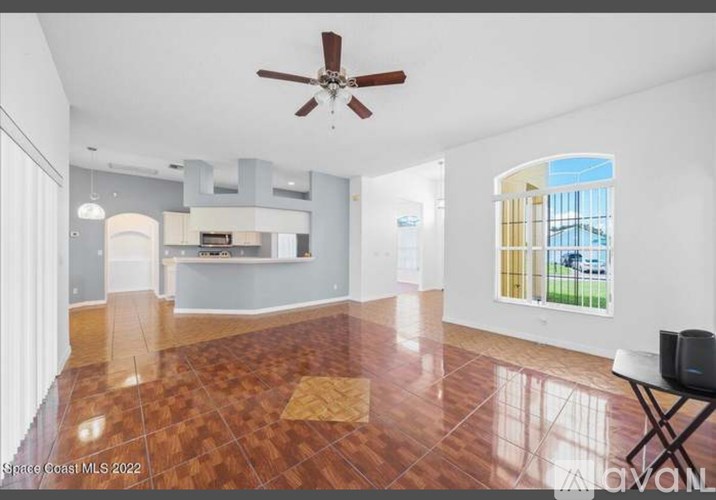 A spacious living room with a ceiling fan and hardwood flooring.