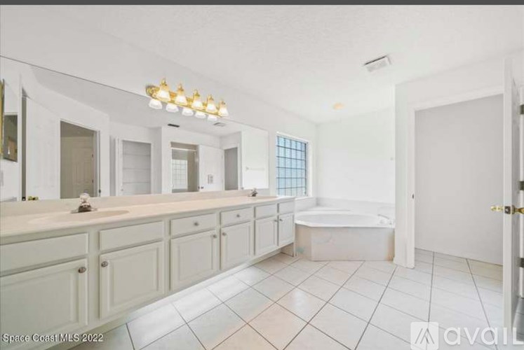 A spacious bathroom with a white tile floor and a bathtub.
