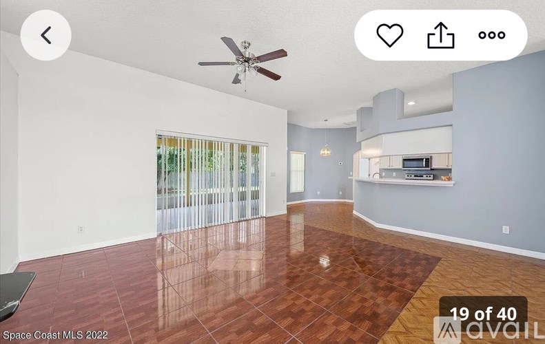 A spacious room with a ceiling fan and a large window with blinds.